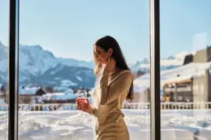 Eine Frau hält ein Weinglas vor dem Bergpanorama.