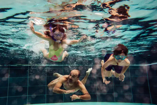 A group of people are swimming underwater at the Werfenweng swimming pool.