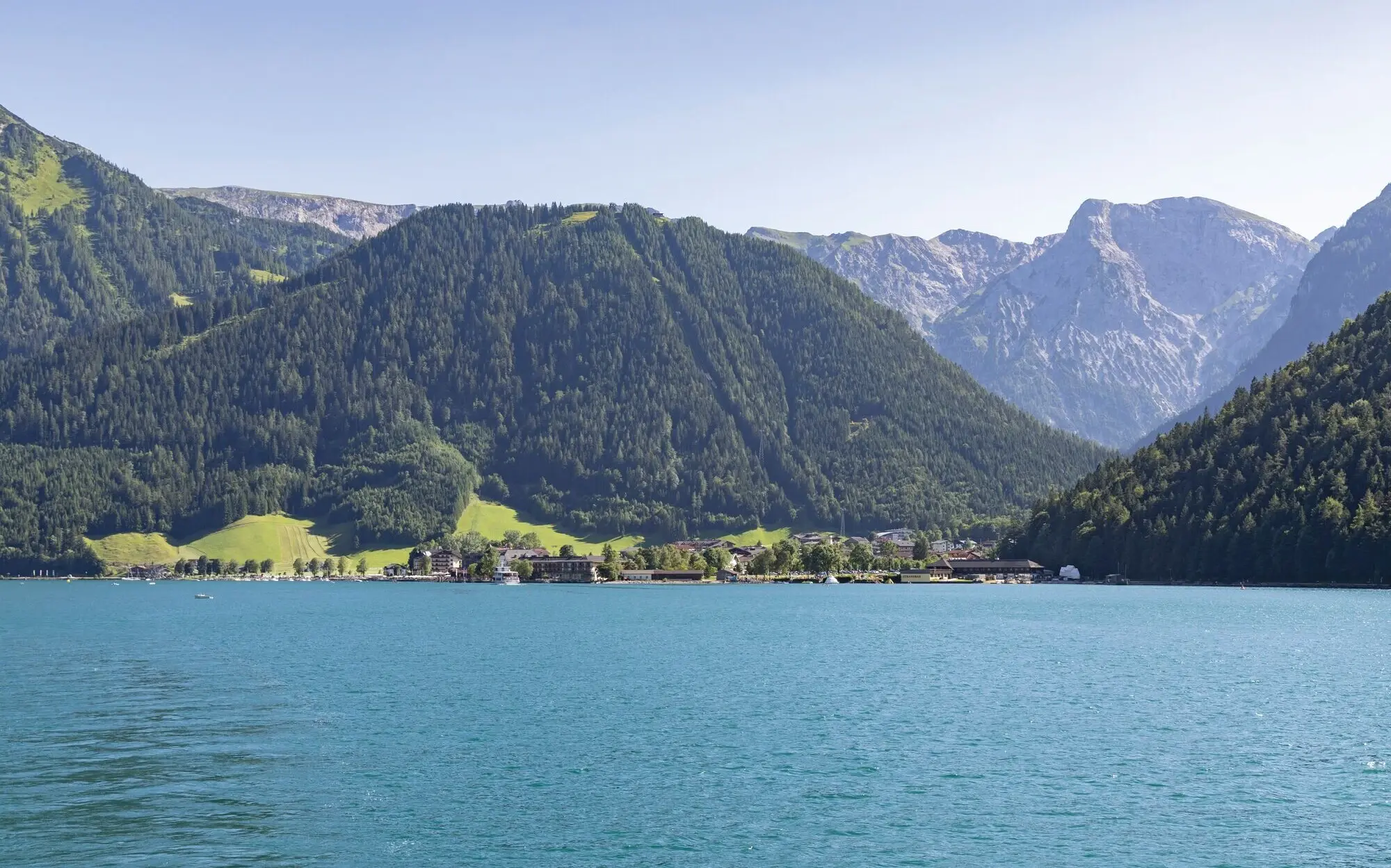 View of Lake Achensee with surrounding mountains and a clear sky.