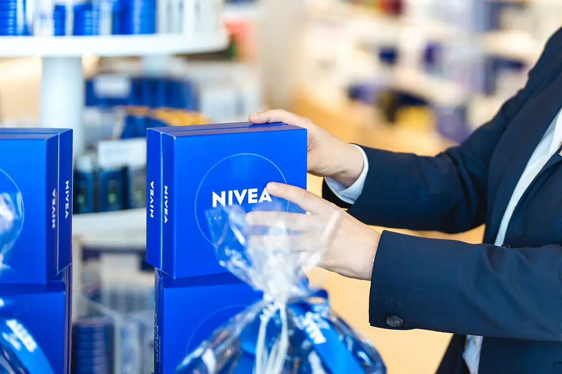A woman in a suit holds a box of NIVEA