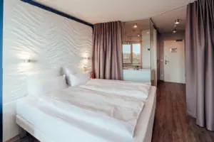 A bed with white sheets and a curtain.
