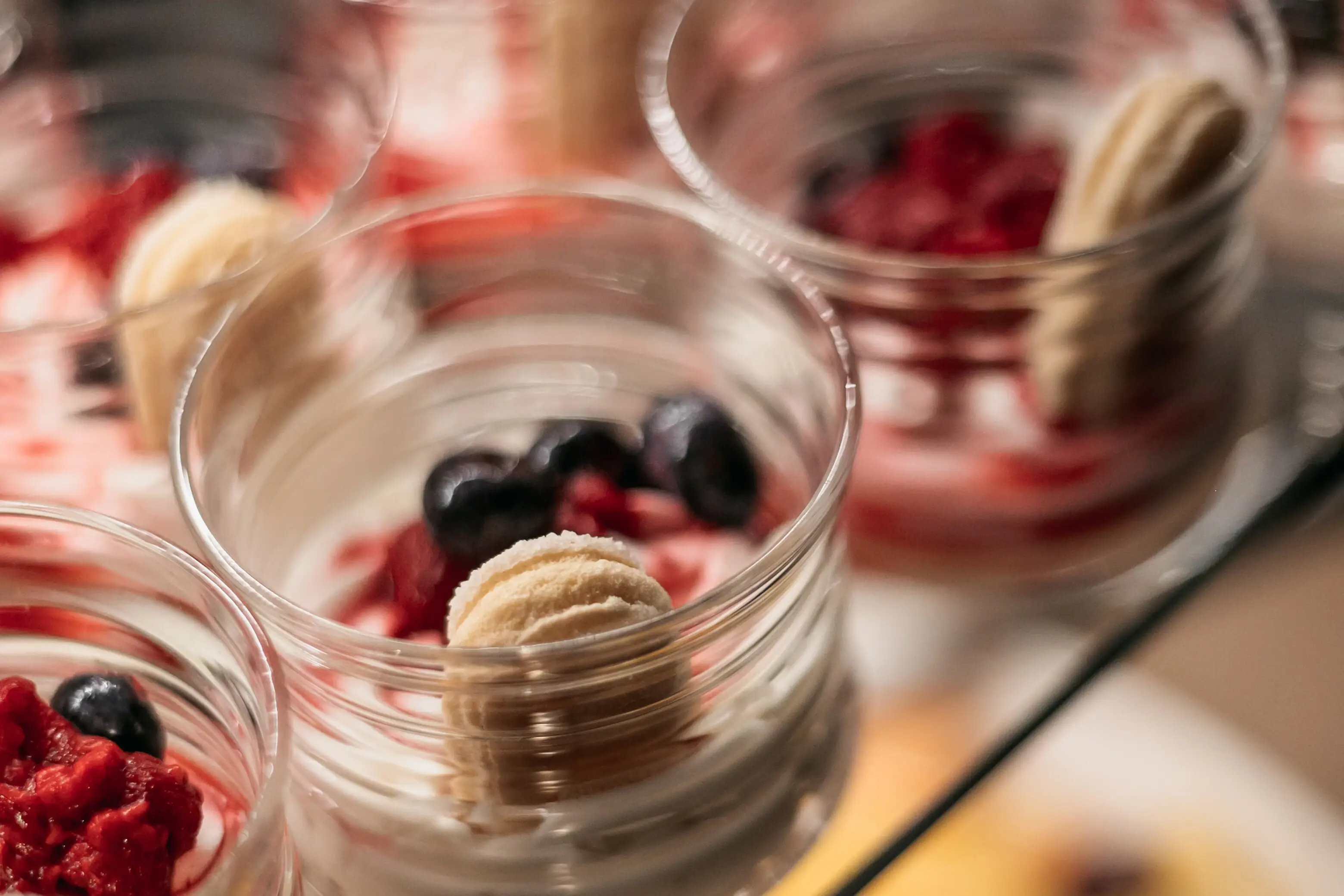A group of dessert glasses with sweet fruit.