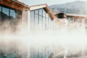 A building in front of a body of water, with a mountain in the background.