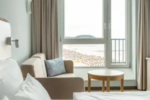 A room with a bed and a sofa, decorated with cushions and curtains.