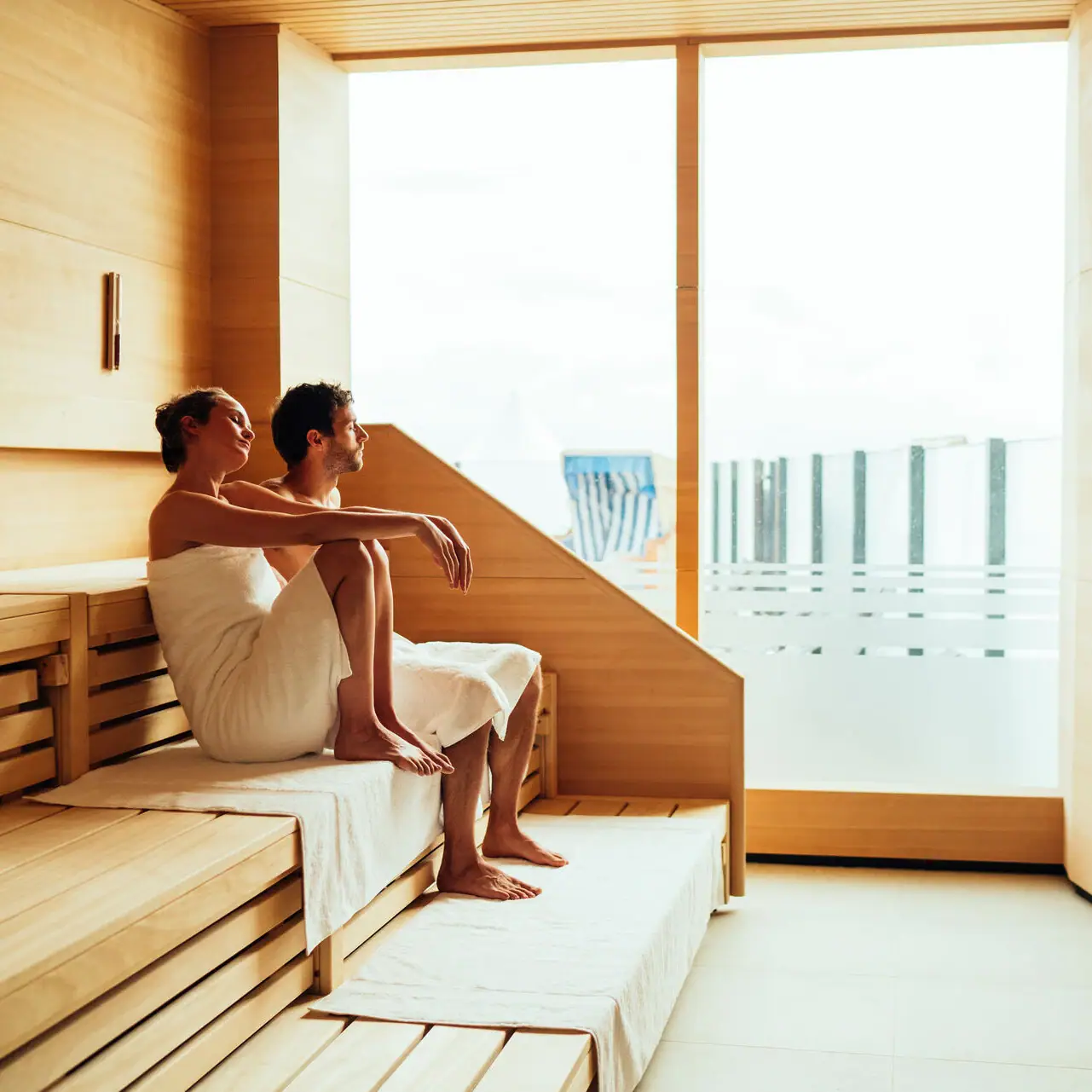 Sauna with a view A man and a woman are sitting on a bench in a sauna.