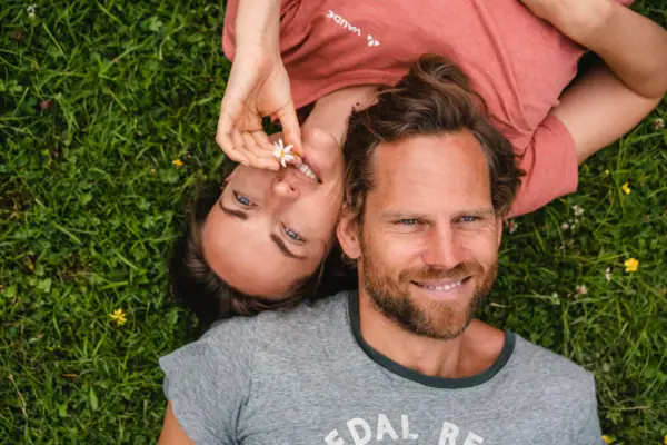 A man and a woman lie smiling on grass.