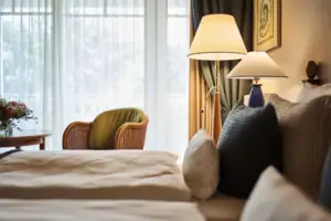 A bed with pillows and a lamp next to a window.