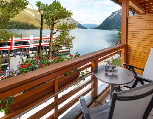 Balcony with a view of Lake Achensee A balcony with a table and chairs overlooking a lake.