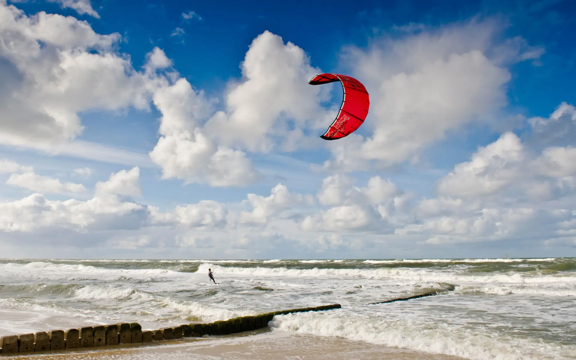 One person kite surfing on wavy water on a sunny day