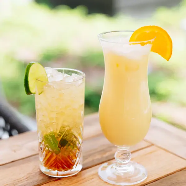 Two glasses with drinks on a table, one with a cocktail set on the terrace of the aja Bar Garmisch-Partenkirchen.