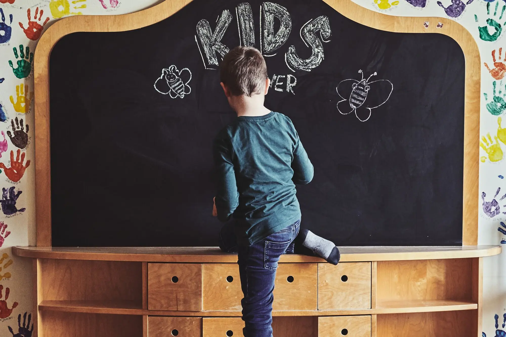 A boy standing on a blackboard indoors.