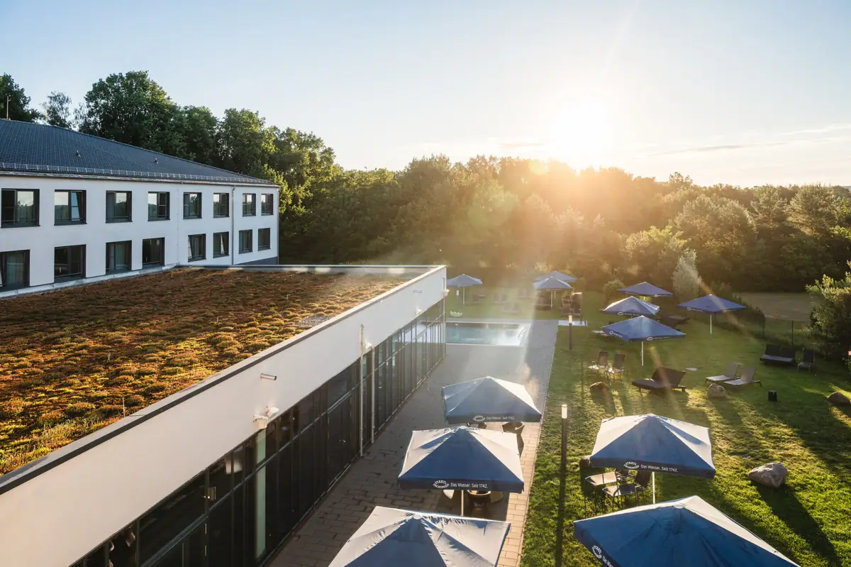 aja Bad Saarow A building with parasols and chairs on a lawn.