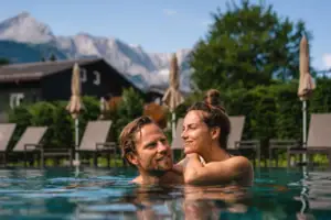 A man and a woman in a pool, smiling.