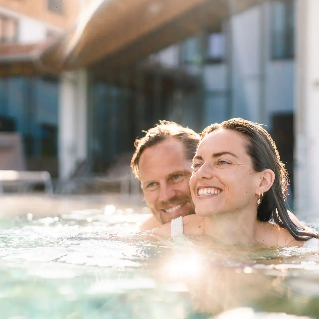 Day SPA in Ruhpolding A man and a woman smiling in a swimming pool.