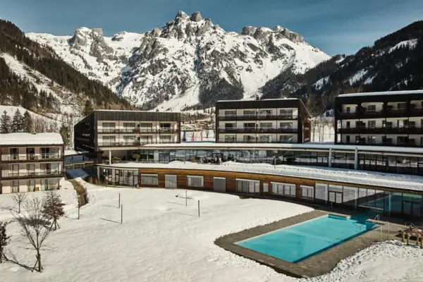 A pool in front of a building with mountains in the background.