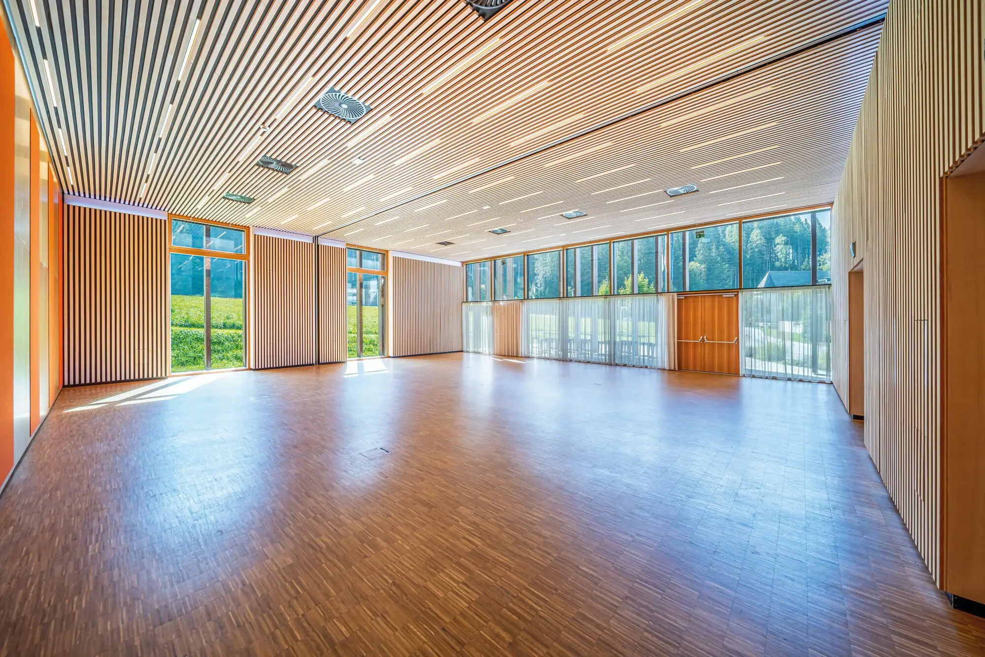Conference campus Large room with wooden floor and windows.
