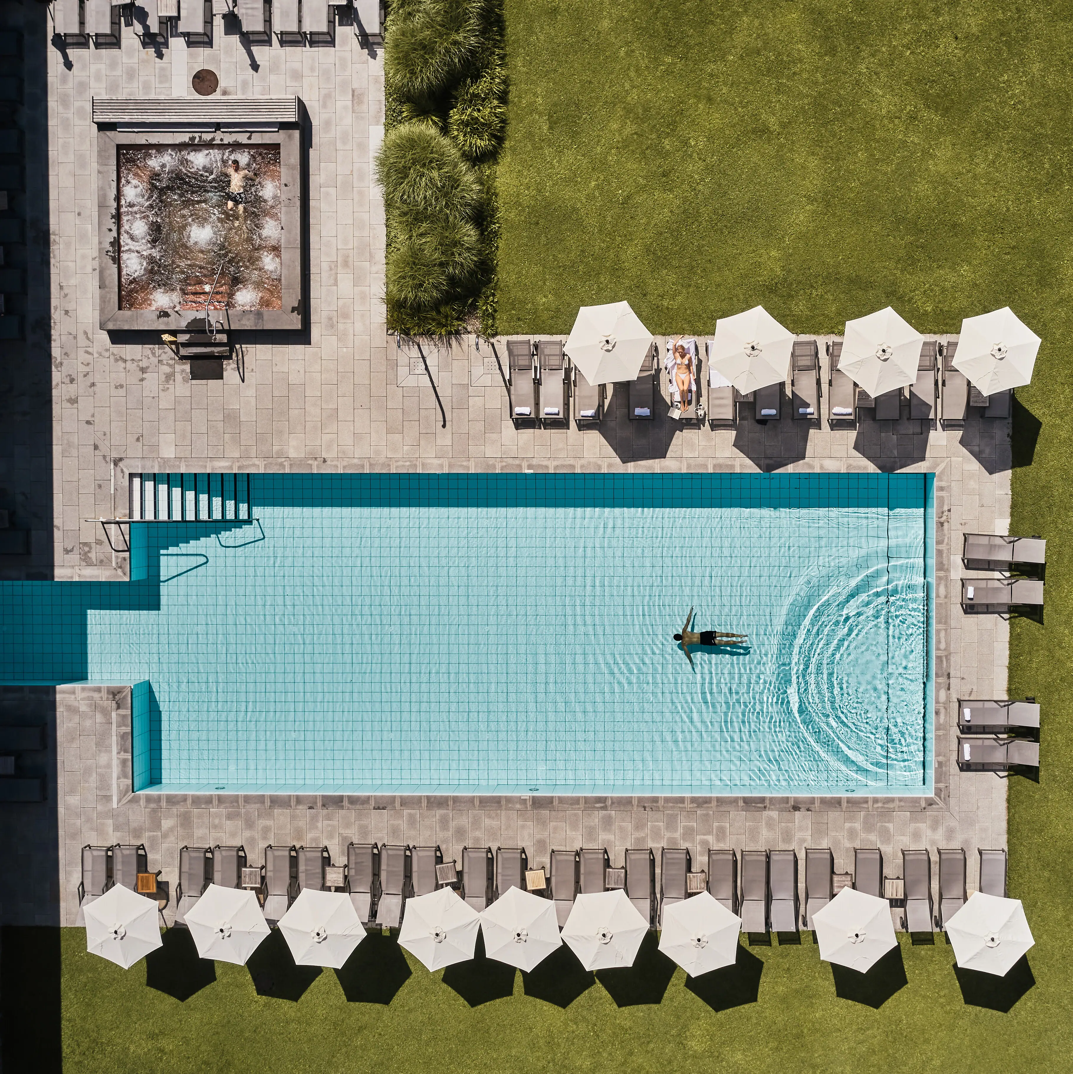 Outdoor pool Bergresort Werfenweng A swimming pool with parasols and grass.