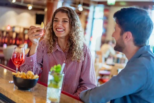 Bar A woman holds a piece of fruit while a man sits at a bar.