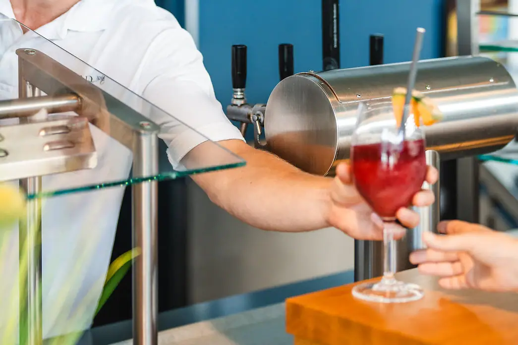 A man hands a customer a drink.