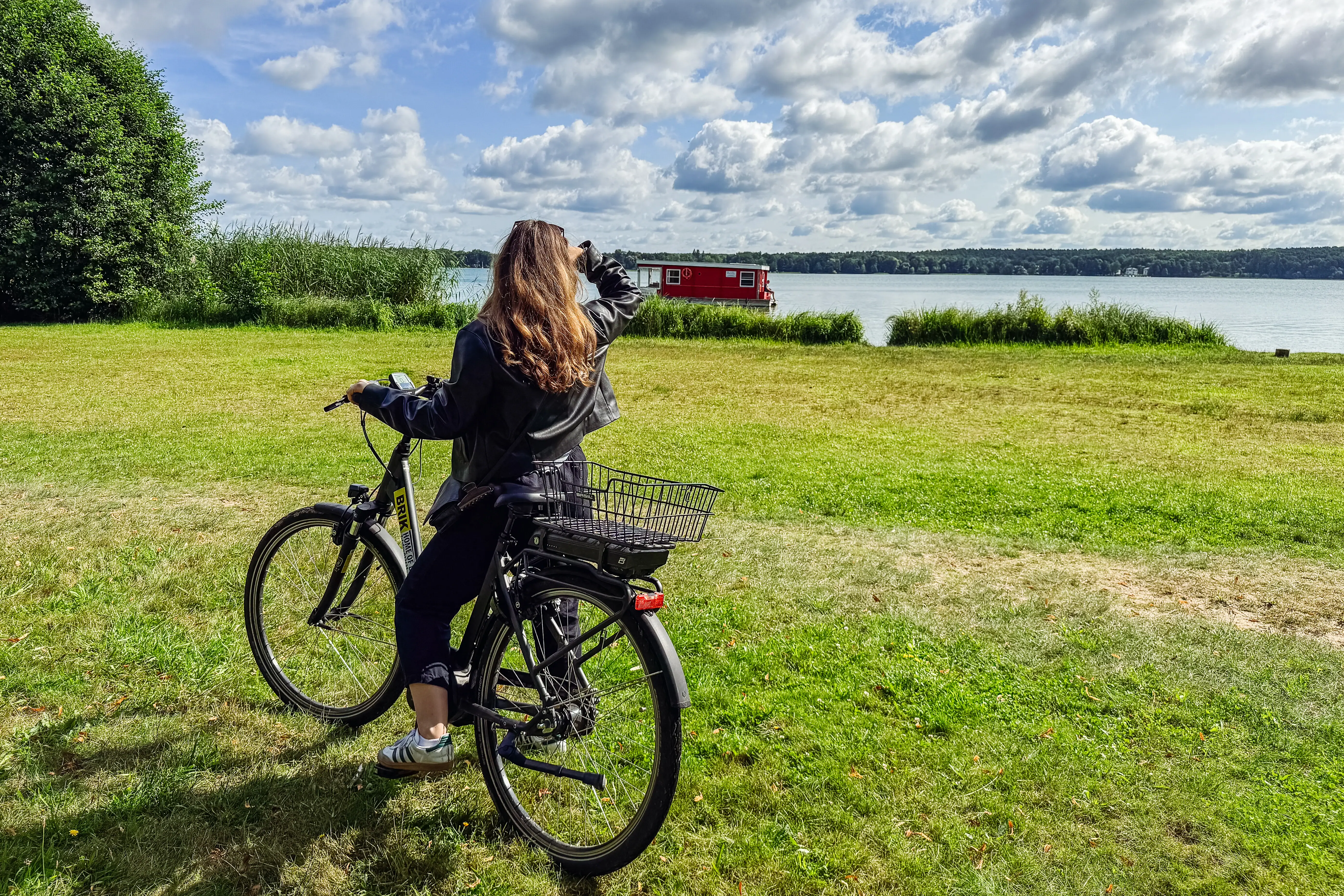 Cycling by the lake Woman stands by the lake with her bike and looks towards the lake.