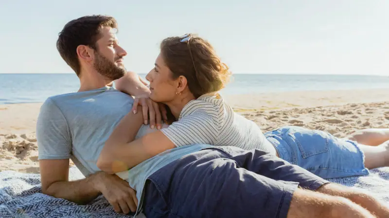 Beach holidays A man and woman lying on the beach, engaged in a romantic kiss.