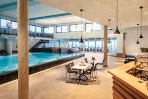 An indoor swimming pool in a building with a ceiling and furniture.