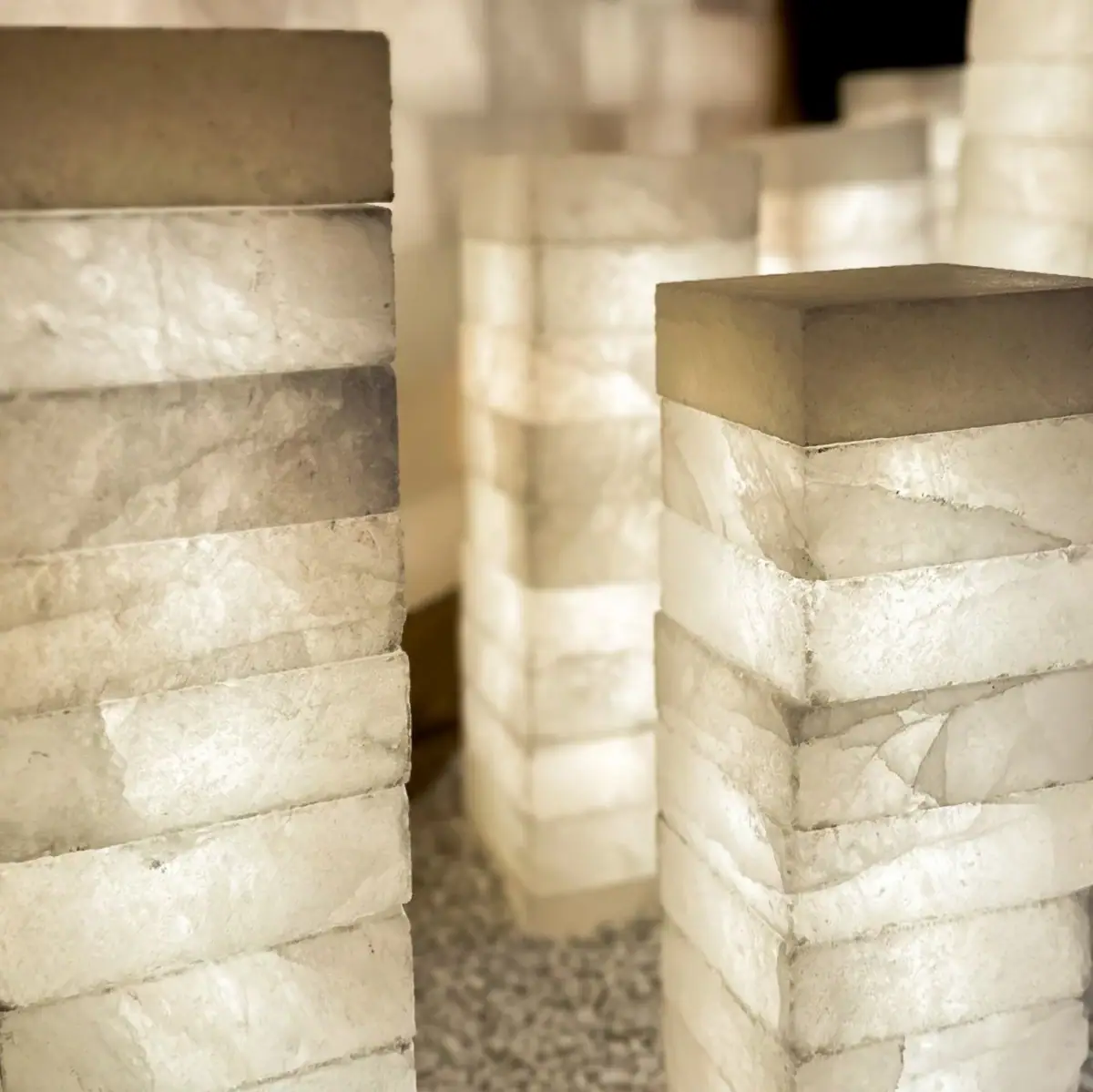 In a dimly lit room, blocks of salt are stacked and illuminated.