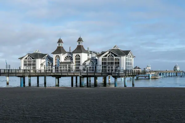 A building on a jetty by the water under a cloudy sky.
