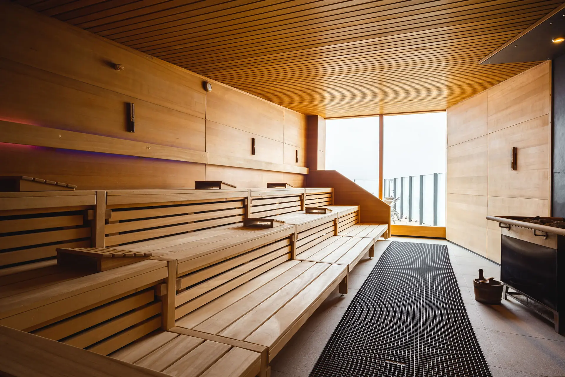 Wooden benches in a sauna room with a window at the end