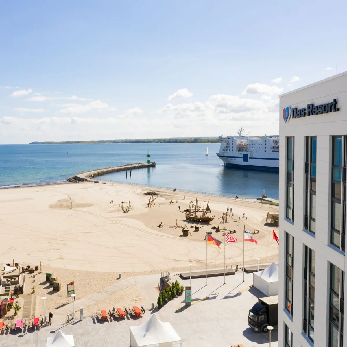 The view from the aja Travemünde overlooking the beach with a ship and a lighthouse.
