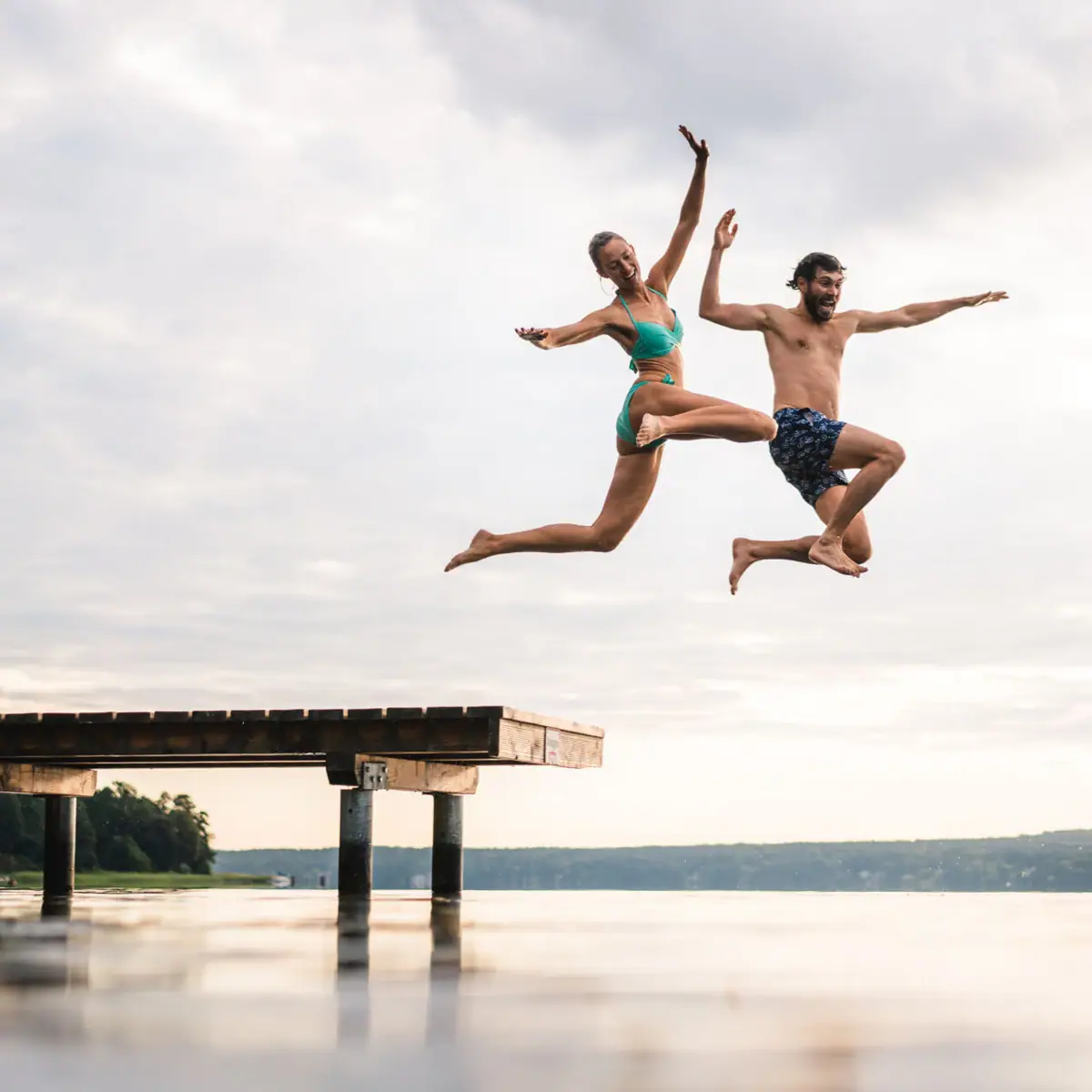 A man and a woman jump into a lake.