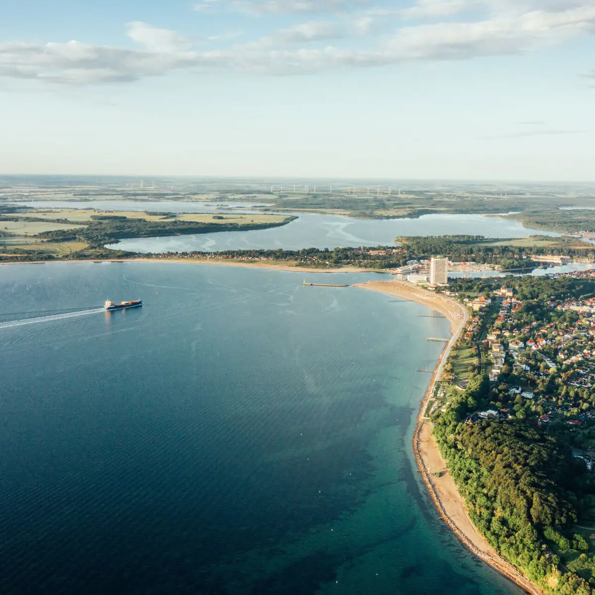 Aerial view of a body of water and a coastal town under a cloudy sky.