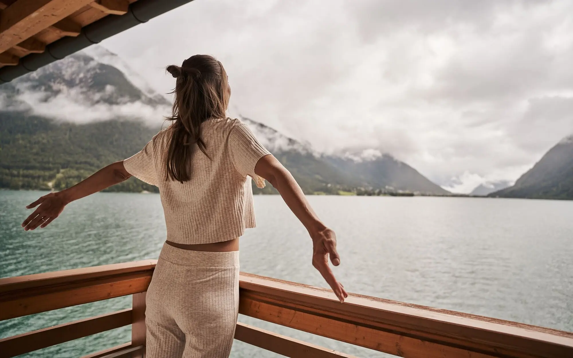 Woman stands on a wooden platform and looks out over Lake Achensee.