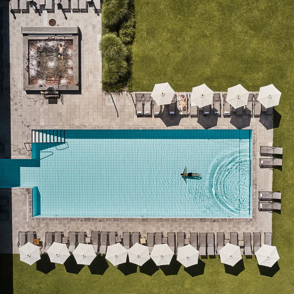 Swimming pool with parasols and lawn.