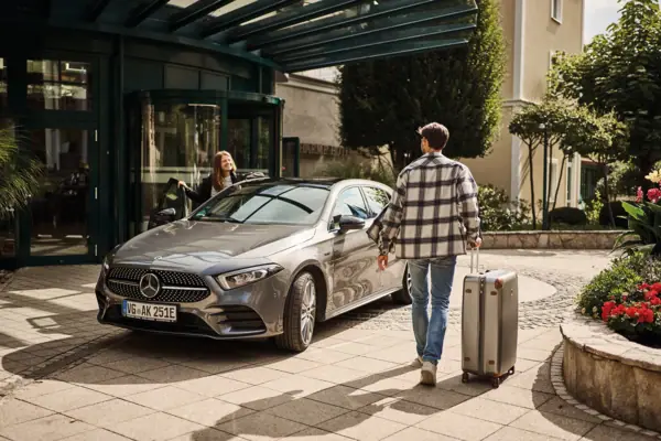 Parking A man and a woman with luggage in front of a car.