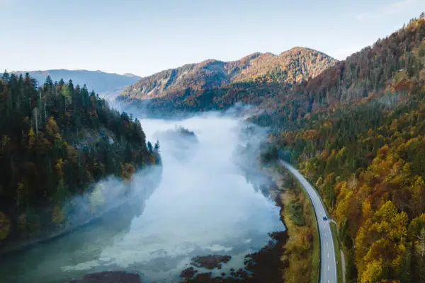Nature in Chiemgau Road and river with fog in an autumn landscape.
