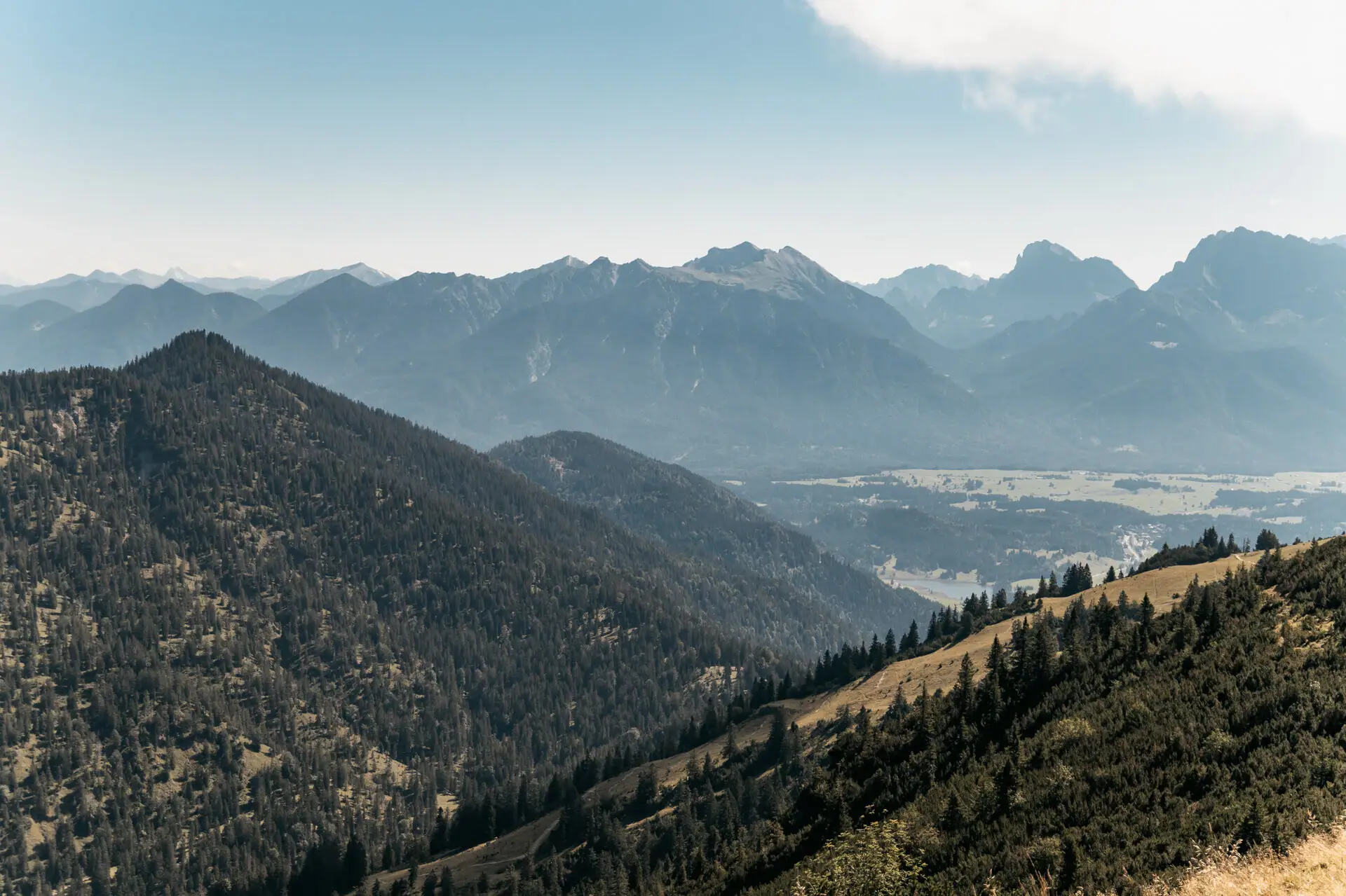 Mountain range with trees and a lake in the foreground.