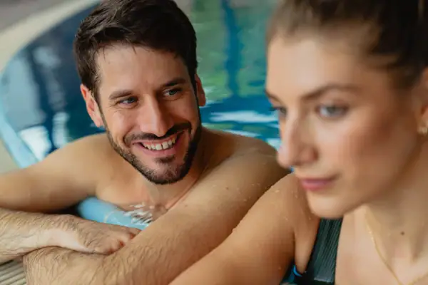 A man and a woman are smiling in the swimming pool.