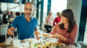 A man and a woman are eating at a table.