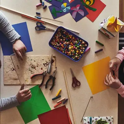 A group of people are sitting at a table with paper and craft materials.