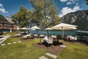 Group of tables and parasols on a meadow on the lakeshore.