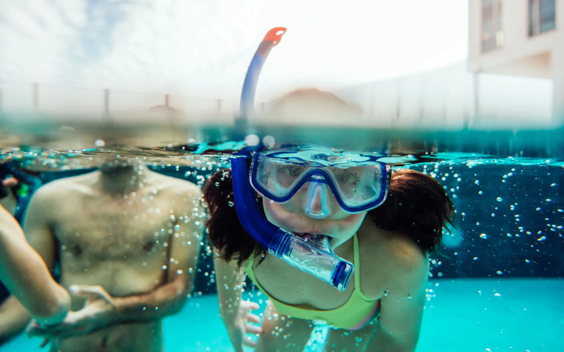 People swimming in a pool wearing diving goggles. 