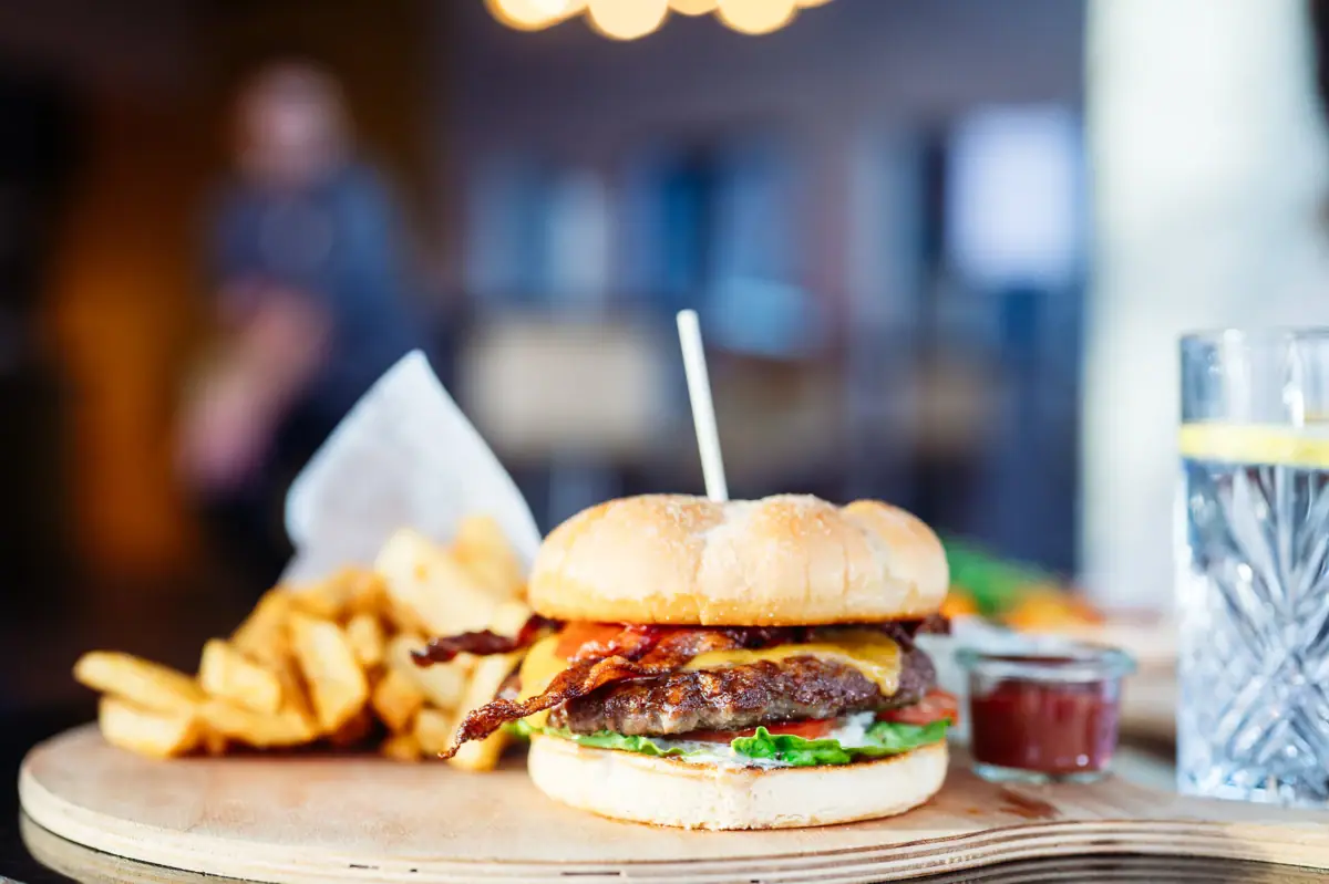A burger with fries on a wooden board.