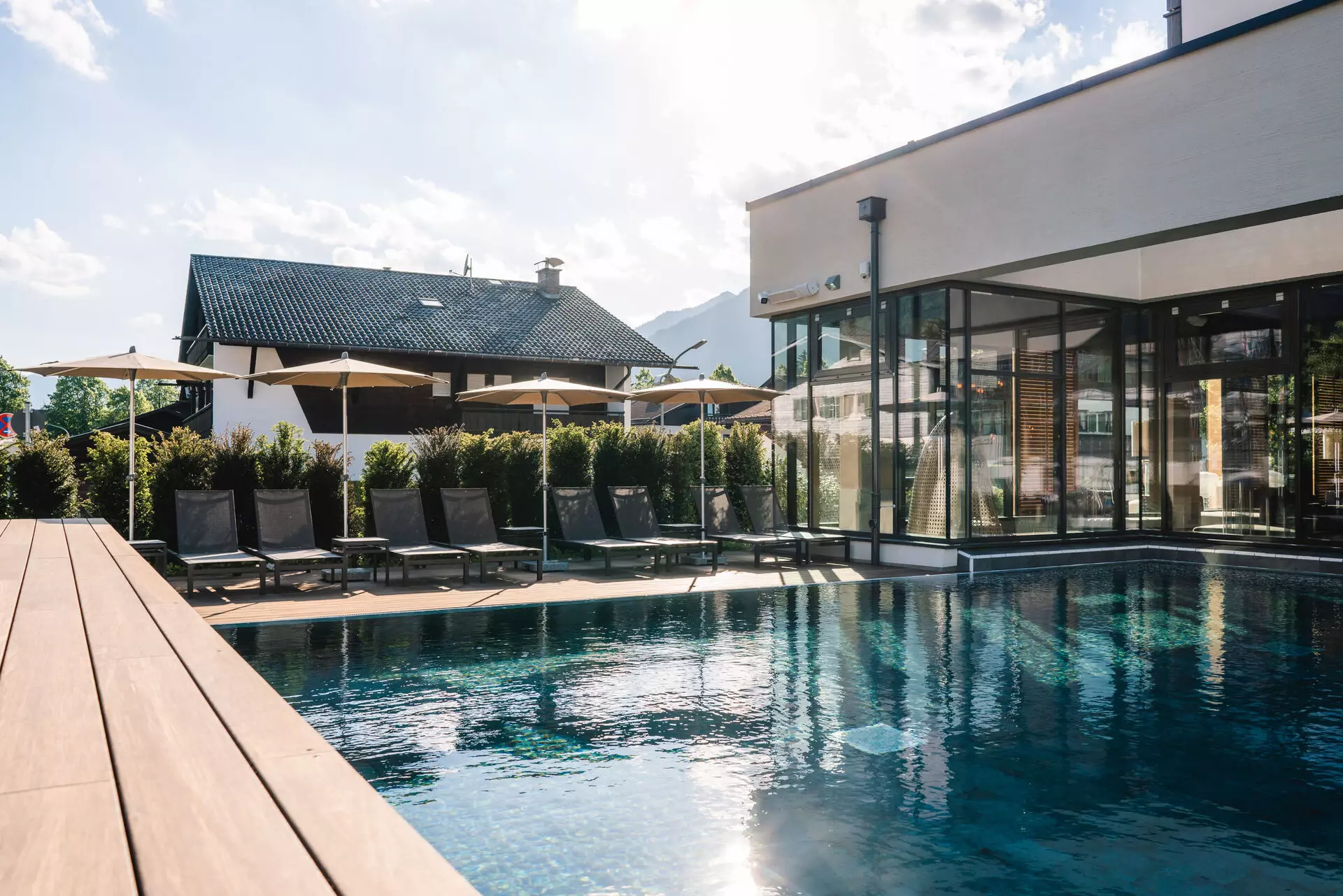 Swimming pool with sun loungers and parasols in front of a building