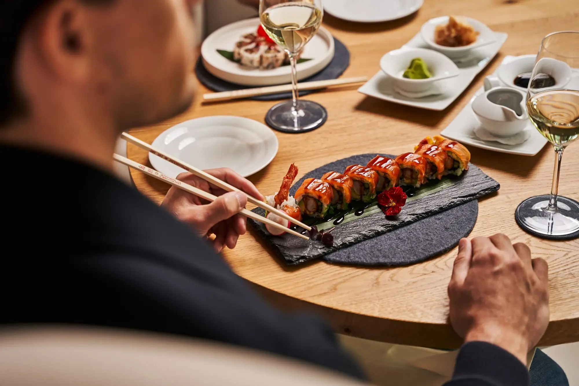 Person eats sushi with chopsticks at a table.