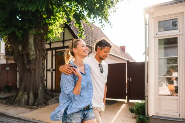 A man and a woman are walking along a pavement.