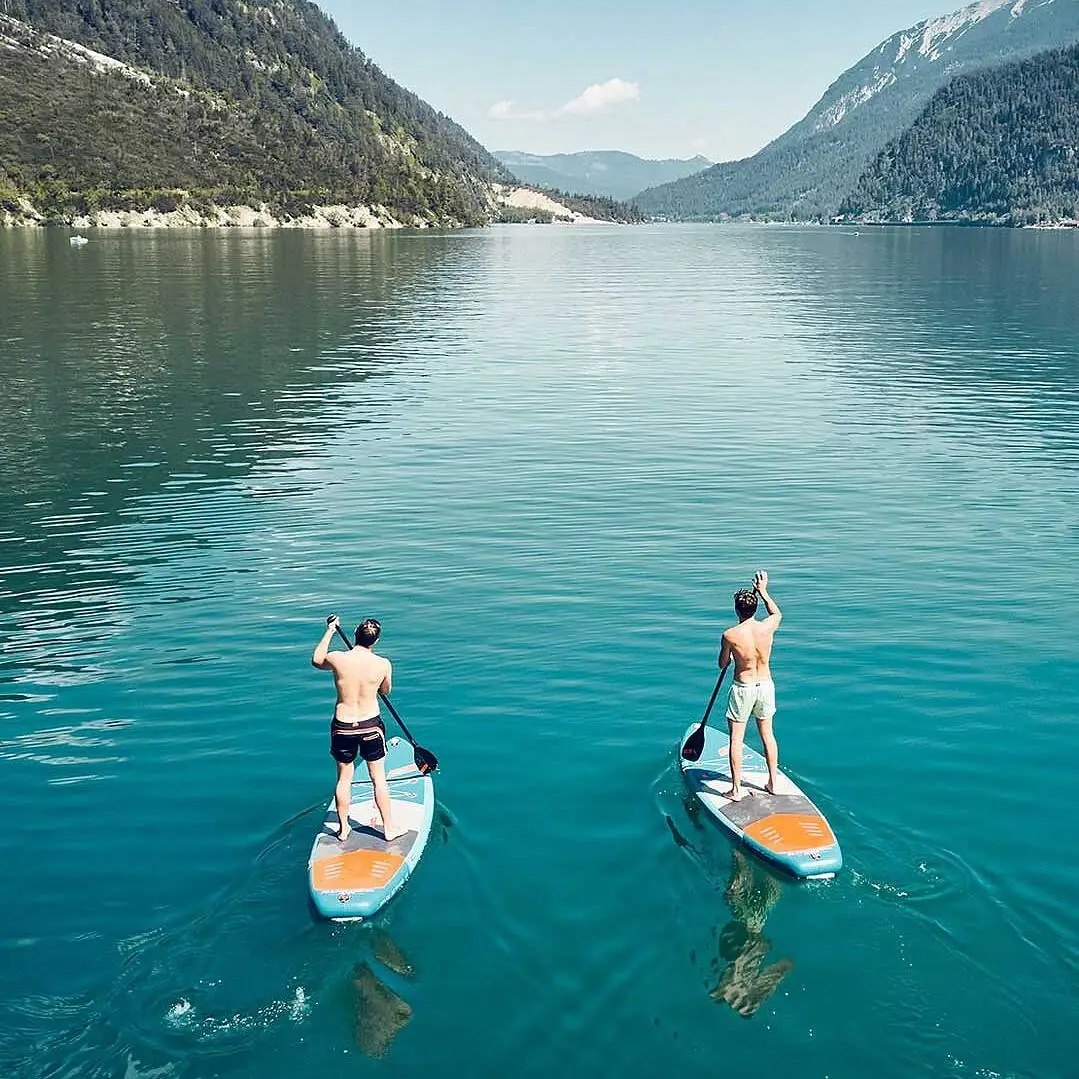 Two men on paddleboards on a lake.