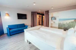 A room with two beds and a blue sofa.