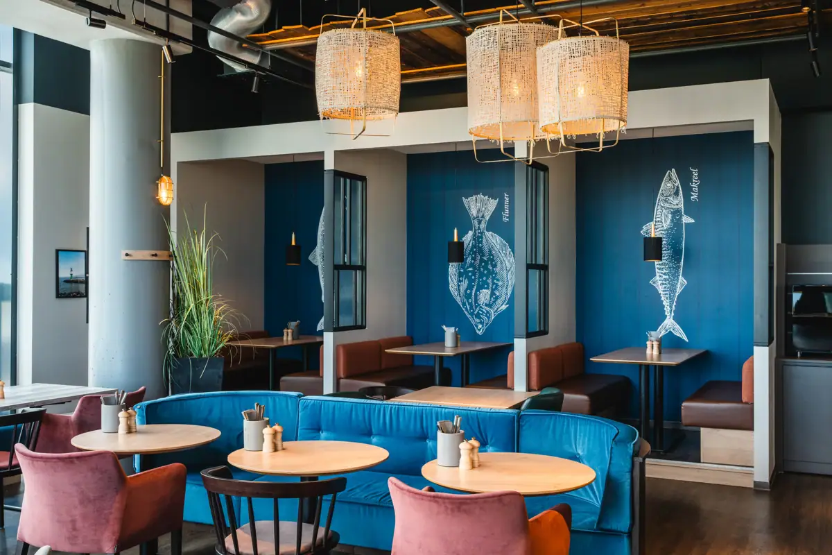 A room with seating niches, decorated in a maritime style and furnished with tables and chairs.