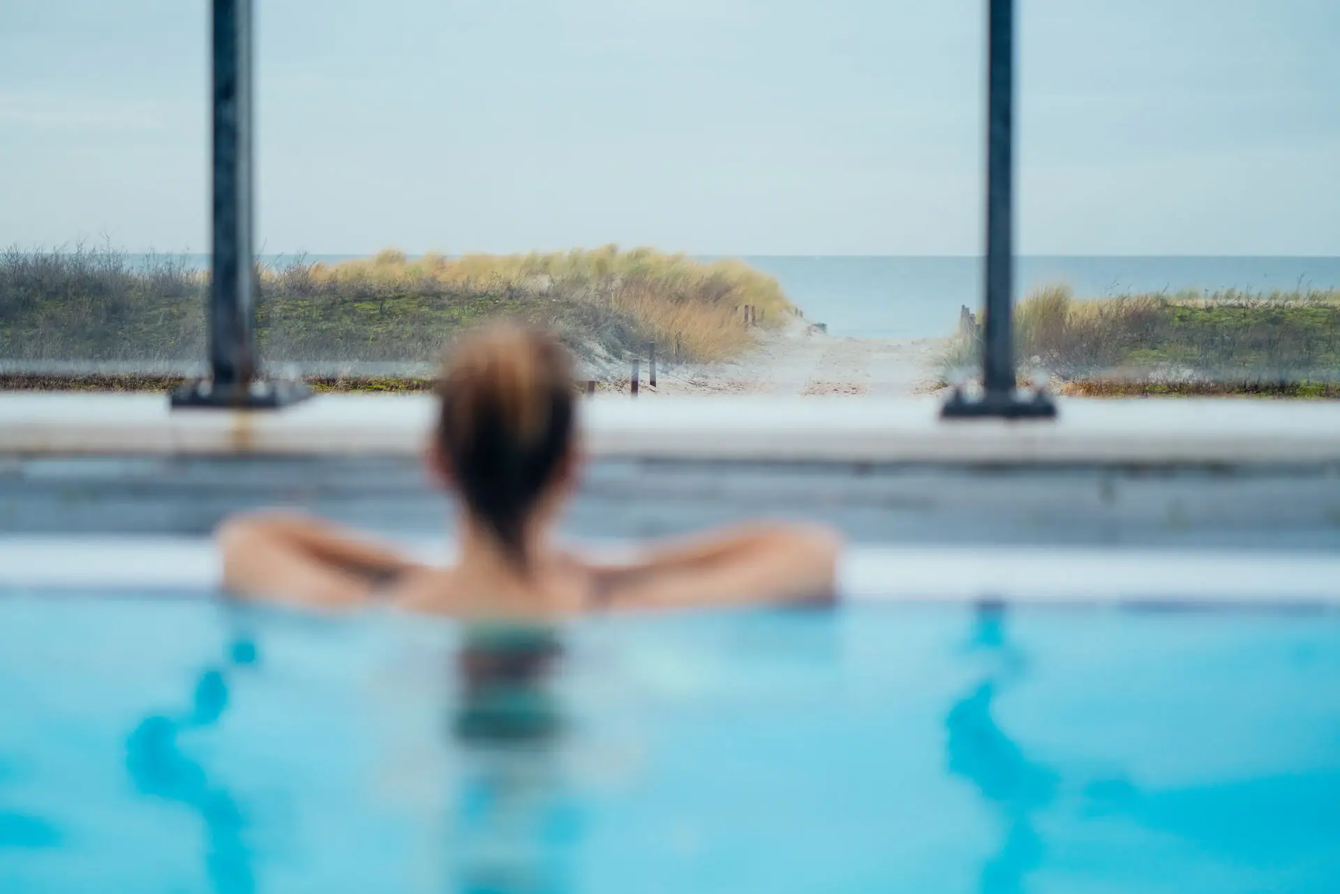Outdoor pool at the aja Warnemünde A woman in the pool looks out over the Baltic Sea.